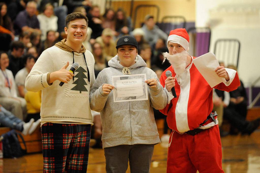Chris Buckla, center, receives free drivers education courses during the Winter Wishes assembly presented by Tommy Hall and Jarrett Allen. Sequim Gazette photo by Matthew Nash