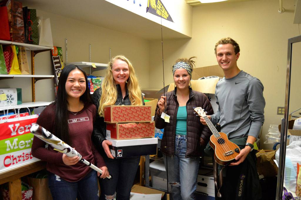 On Dec. 18, Sequim High Leadership students, from left, Shayli Schuman, Allison Van De Wege, Alissa Lofstrom and Liam Payne ready gifts for unsuspecting students at the Winter Wishes assembly the next morning. To mix it up this year, a few presents were given away at the assembly like a bat, shoes, and fishing pole but others were given away later in the day. Sequim Gazette photo by Matthew Nash