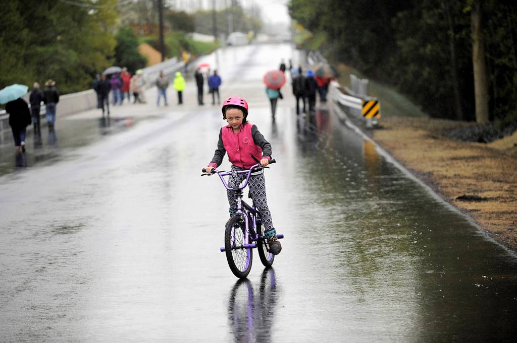 Montana Mathis of Sequim rides her bike on the McDonald Creek Bridge. The bridge reopened on May 1 after a $3 million, months-long replacement project. Sequim Gazette file photos by Matthew Nash