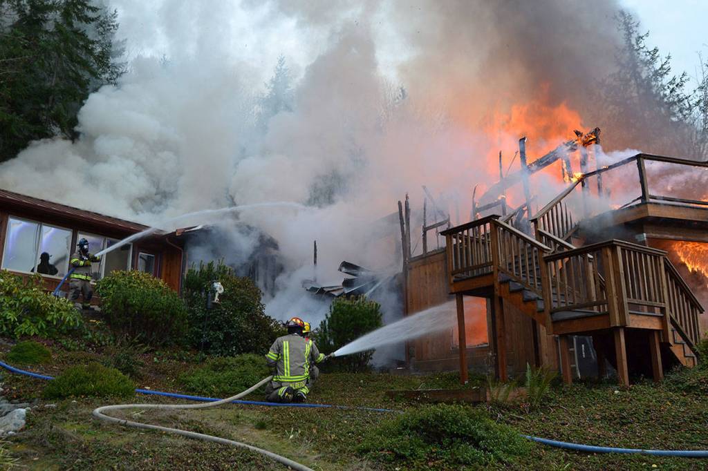 Firefighters from Clallam Fire District No. 3 spray down a residential blaze Monday in Blyn. Sequim Gazette file photo by Matthew Nash