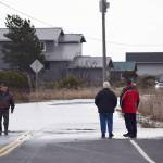 Dwayne Pettett, a nearby resident of 3 Crabs Road, left, wades through about 1 foot deep of water on 3 Crabs Road after high tides and storm surge caused water to flood parts of the area around noon on Dec. 20. Sequim Gazette file photo by Erin Hawkins
