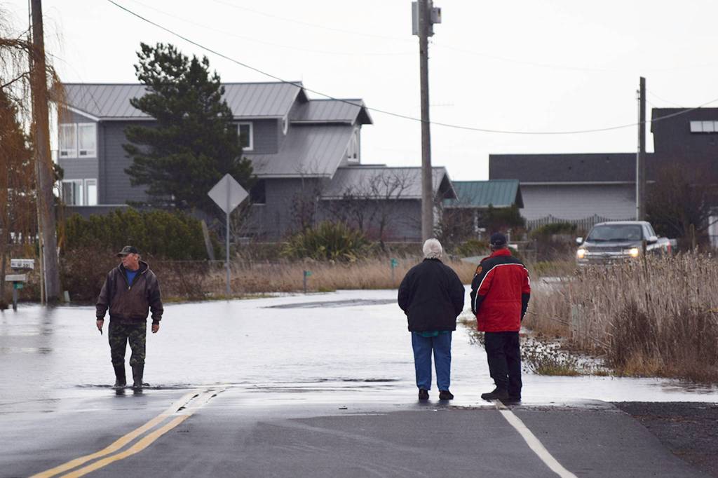 Dwayne Pettett, a nearby resident of 3 Crabs Road, left, wades through about 1 foot deep of water on 3 Crabs Road after high tides and storm surge caused water to flood parts of the area around noon on Dec. 20. Sequim Gazette file photo by Erin Hawkins