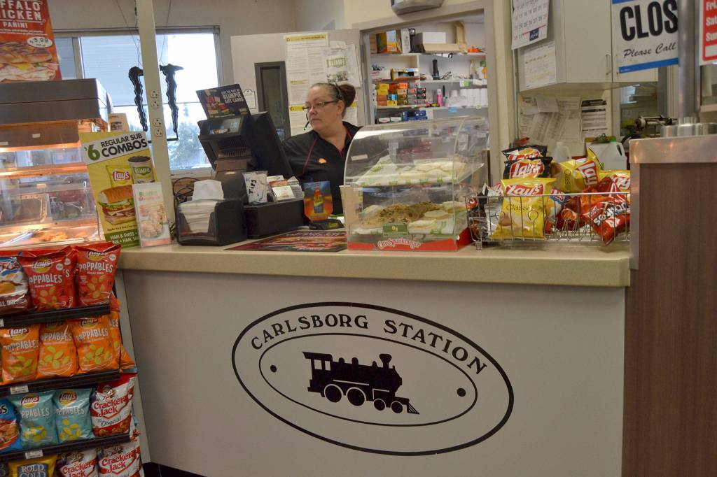Christina Turner rings up a customer inside the Carlsborg Station that serves as a gas station, convenience store and Blimpies sandwich shop. She and other employees say theyve only heard Carlsborg pronounced as Carlsberg. Sequim Gazette photo by Matthew Nash