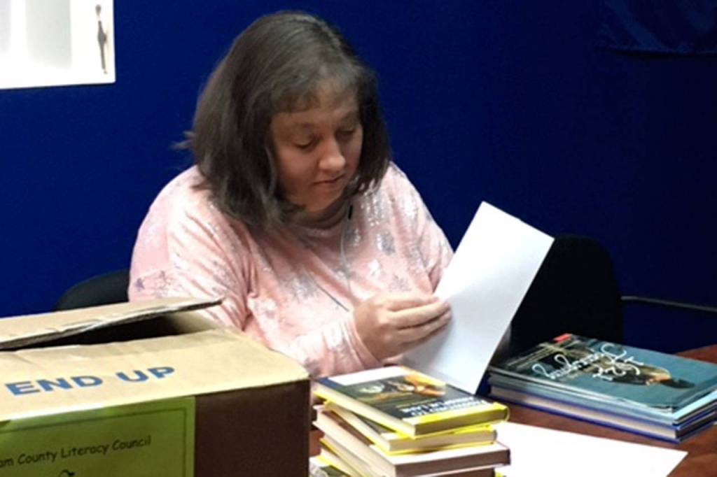 Genny Lopez, a Clallam County Literacy Council board member, labels new books with the Literacy Councils sticker encouraging people to Read to your child 20 minutes a day. Thousands of the Literacy Councils books are distributed across the county each year. Submitted photo