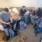 Jacob Olson, left, looks through Magic the Gathering cards while Colleen and Ted Chapman read at Serenity House of Clallam Countys night-by-night shelter Thursday. The shelter is open 24/7 while temperatures stay below freezing. (Jesse Major/Peninsula Daily News)