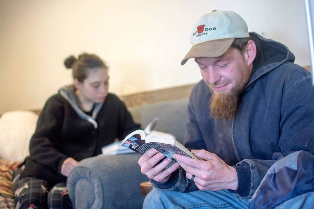 Colleen and Ted Chapman read together while staying at Serenity House of Clallam Countys night-by-night shelter Thursday. The shelter is open 24/7 while temperatures stay below freezing. (Jesse Major/Peninsula Daily News)