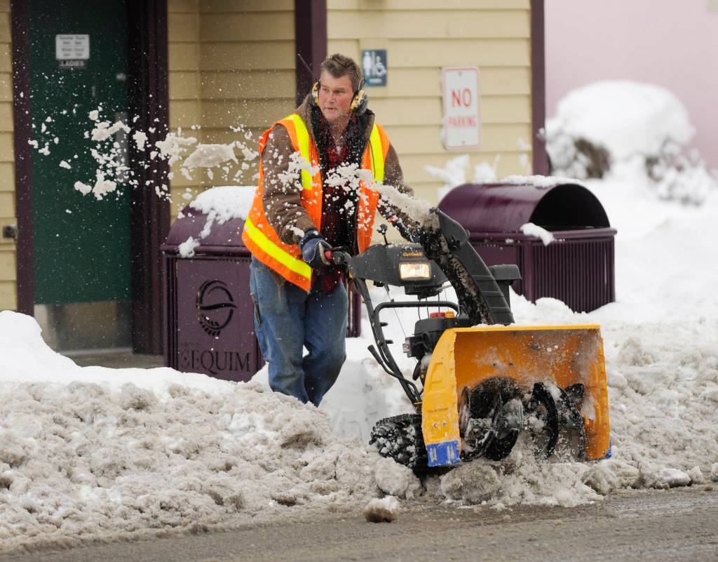 City of Sequim staffer Gary Butler helps clear sidewalks near the Sequim Civic Center Tuesday morning. Sequim Gazette photo by Michael Dashiell