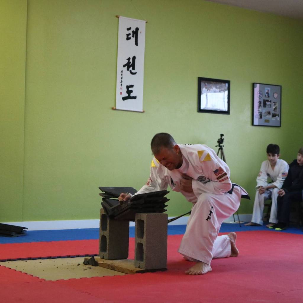 Larry Muckley breaks concrete tiles to display power during his black belt testing earlier this month. He earned his 2nd degree black belt. Submitted photo