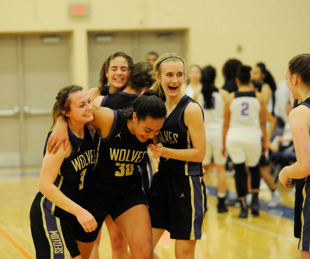 Sequims Bobbi Sparks, left, and Hannah Wagner help Jayla Julmist (30) off the court following a wild, 54-44 Sequim win in the regional round of the state 2A tournament against Foster on Feb. 22 in Auburn. Sequim Gazette photo by Michael Dashiell