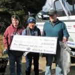 Mark Thompson, right, holds his 19.35-pound blackmouth salmon that earned the $10,000 first prize at the 2019 Olympic Peninsula Salmon Derby. His wife Kristi Thompson is at left, with Kathy Watrous, Gardiner Salmon Derby Association President, holding Thompsons $10,000 check. The trio is standing in front of the 2019 Northwest Salmon Derby Series Grand Prize Boat valued at $75,000; each derby entrant received an entry for the boat drawing which will be held in September. Submitted photo