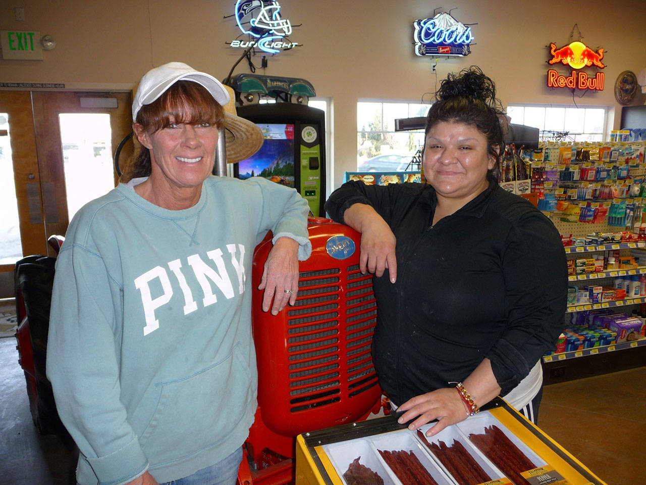 Hardys Market managers Shelly Cassalery, left, and Sendy Alvarez welcome customers at the stores antique tractor. Photo by Patricia Morrison Coate