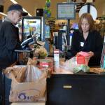 Kathy Johnson, a checker at Sequim QFC, helps Jack Guinn purchase his groceries on March 18. Starting April 1, QFC will no longer offer plastic bags at checkout stands to customers. Guinn said hes been in the habit of using reusable bags since his former home of Shoreline banned the bags. Currently, no ban is proposed in Sequim. Sequim Gazette photo by Matthew Nash