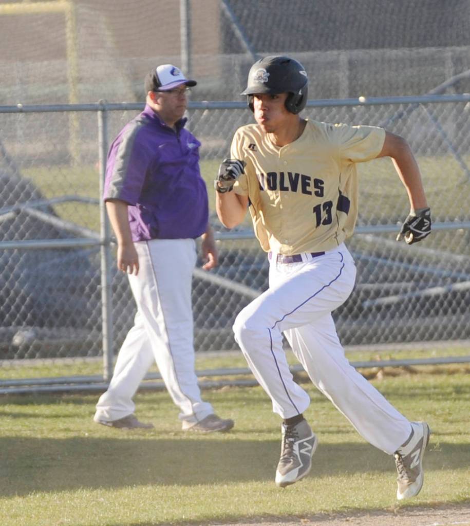As Sequim coach Dave Ditlefsen looks on, SHSs Hayden Eaton rounds third base and scores late in the Wolves 10-1 win over North Mason on March 20. Sequim Gazette photo by Michael Dashiell