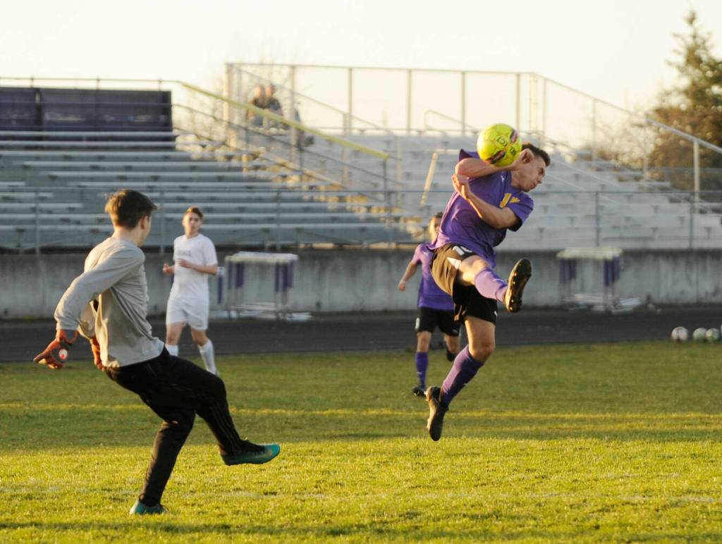 Sequims Mathys Tanche, right, looks to avoid contact as North Kitsap keeper Zach Coleman clears the ball in the first half of the Wolves 6-0 win over the Vikings on March 20. Sequim Gazette photo by Michael Dashiell