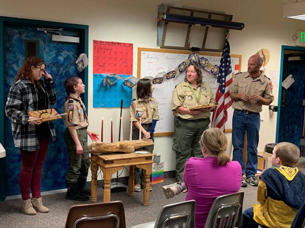 Eleven-year-olds Loralynn Chrisinger and Lindsey Anderson receive congratulations from their moms, Bethany Chrisinger, on left, and Kathryn Anderson, second from right, next to pack leader Paul Rynearson in early March. Photo courtesy of Amy Emett