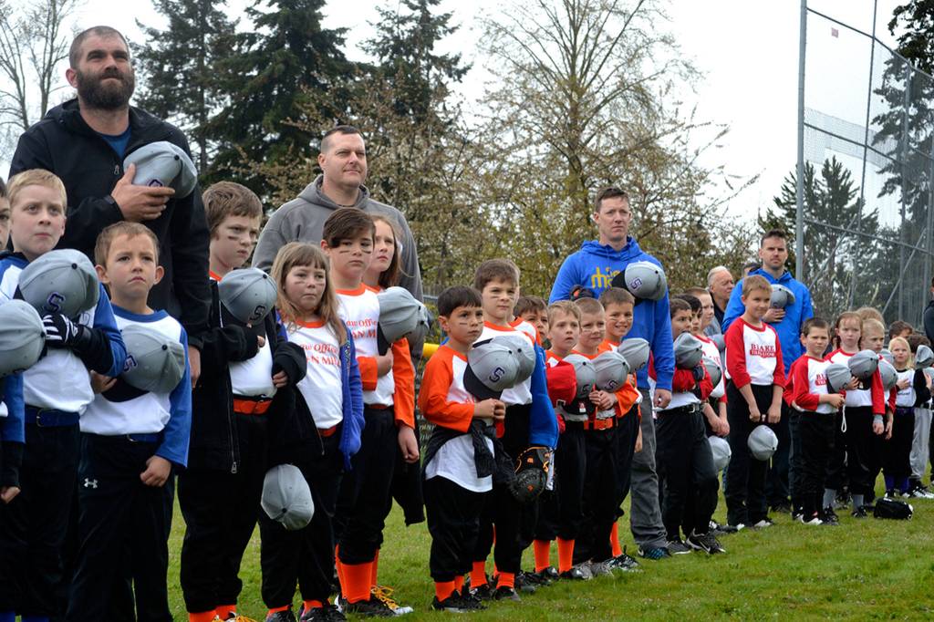 Players and coaches stand at attention in respect during the singing of The Star-Spangled Banner by Ava Bower at Sequim Little Leagues opening day ceremony. Sequim Gazette photo by Matthew Nash