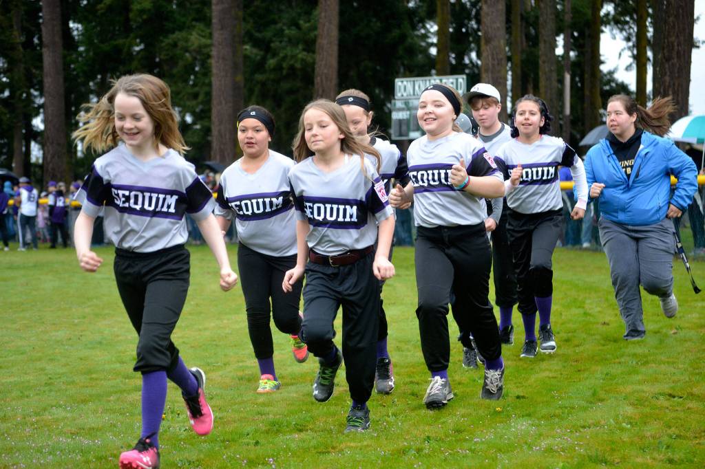 The Minor Girls team of The Law Office of Alan Millet coached by Derek Sanderson run hard for their season debut during the Player Procession for Sequim Little Leagues Opening Day Ceremony on April 13.