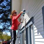 Julie McCrorie with Sequim Community Church paints the exterior of the Sequim-Dungeness Hospital Guild during the Sequim Beautiful Day volunteer effort.