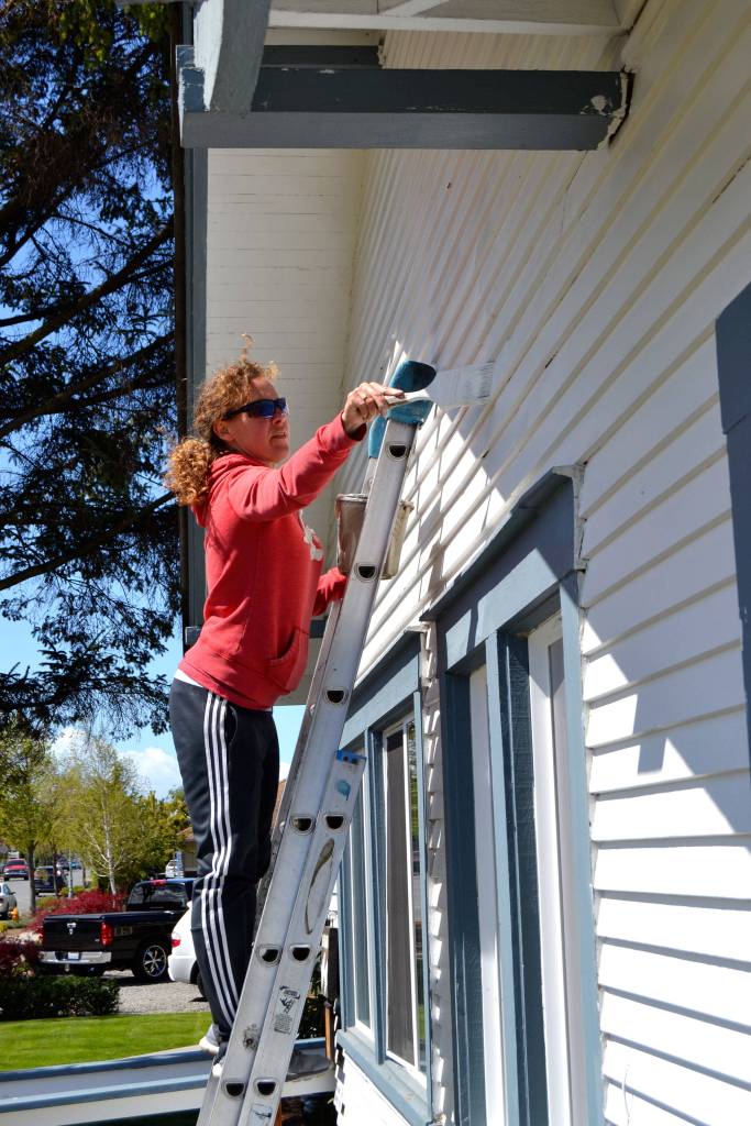 Julie McCrorie with Sequim Community Church paints the exterior of the Sequim-Dungeness Hospital Guild during the Sequim Beautiful Day volunteer effort.