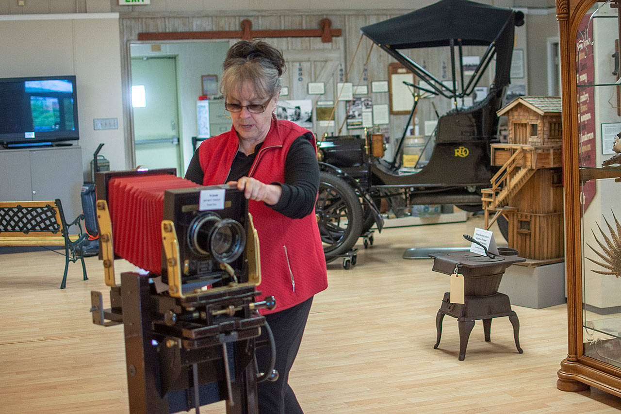 Judy Reandeau Stipe, executive director of the Sequim Museum and Arts Center, moves a camera on display at the museum Sunday. Photo by Jesse Major/Peninsula Daily News