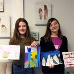 Olympic Christian School students Ellie Smith, left, and Coco Broker display some of their artwork at the schools recent Art Festival. Smith took top honors in the seventh-/eighth-grade division with her Galactic Gradients painting, while Broker placed second with her painting, The Magnificent Mountains. Photo courtesy of Olympic Christian School