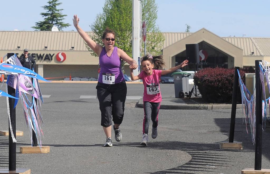 Ceci and Mia Buhrer celebrate as they cross the finish line after finishing the Sequim Irrigation Fun Run 1-mile race on May 11. Sequim Gazette photo by Michael Dashiell