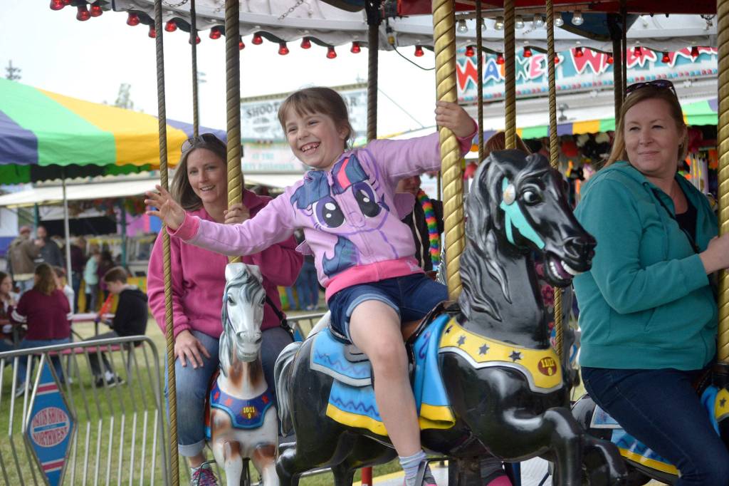 Alyssa LAmi, 7, of Sequim waves to her dad while riding the Merry-Go-Round with her mom Riki, right, on Mothers Day at the Irrigation Festivals carnival. Sequim Gazette photo by Matthew Nash