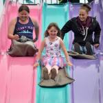 Sisters Angel, 13, and Savannah Wagner, 8, race their mom Natalie Topham down the Super Slide on Mothers Day. Sequim Gazette photo by Matthew Nash