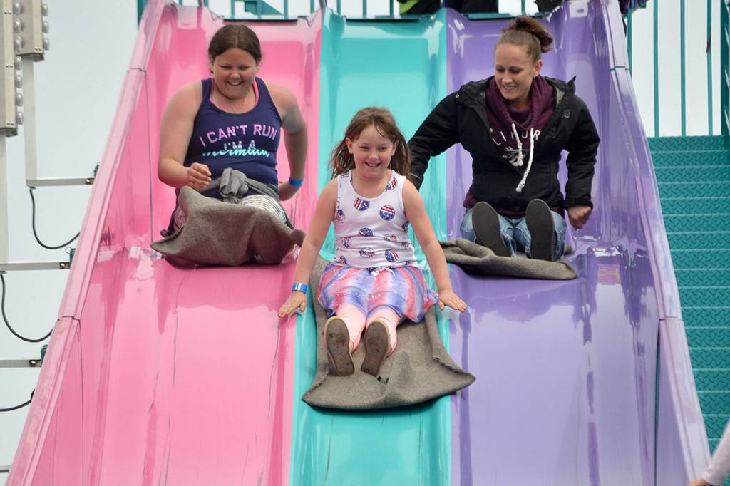 Sisters Angel, 13, and Savannah Wagner, 8, race their mom Natalie Topham down the Super Slide on Mothers Day. Sequim Gazette photo by Matthew Nash