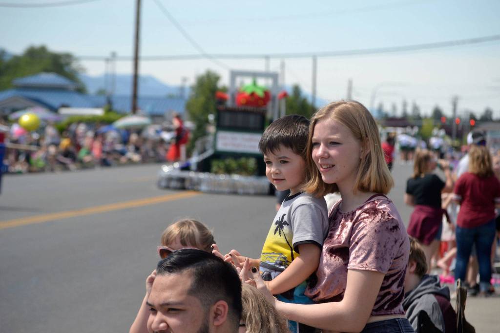 Hailey Collier, 15, holds her nephew River Bogie, 3, as they watch bands and floats go by in the Irrigation Festivals Grand Parade. Sequim Gazette photo by Matthew Nash
