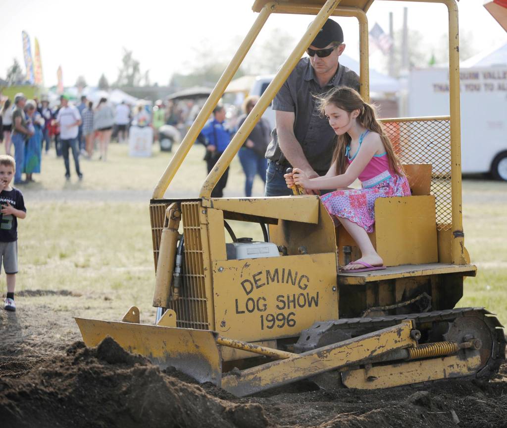 Nelson Bekkevar helps Adalie Eastburn, 9, of Sequim, move a bit of dirt at the Sequim Irrigation Festival Logging Show on May 11. Sequim Gazette photo by Michael Dashiell