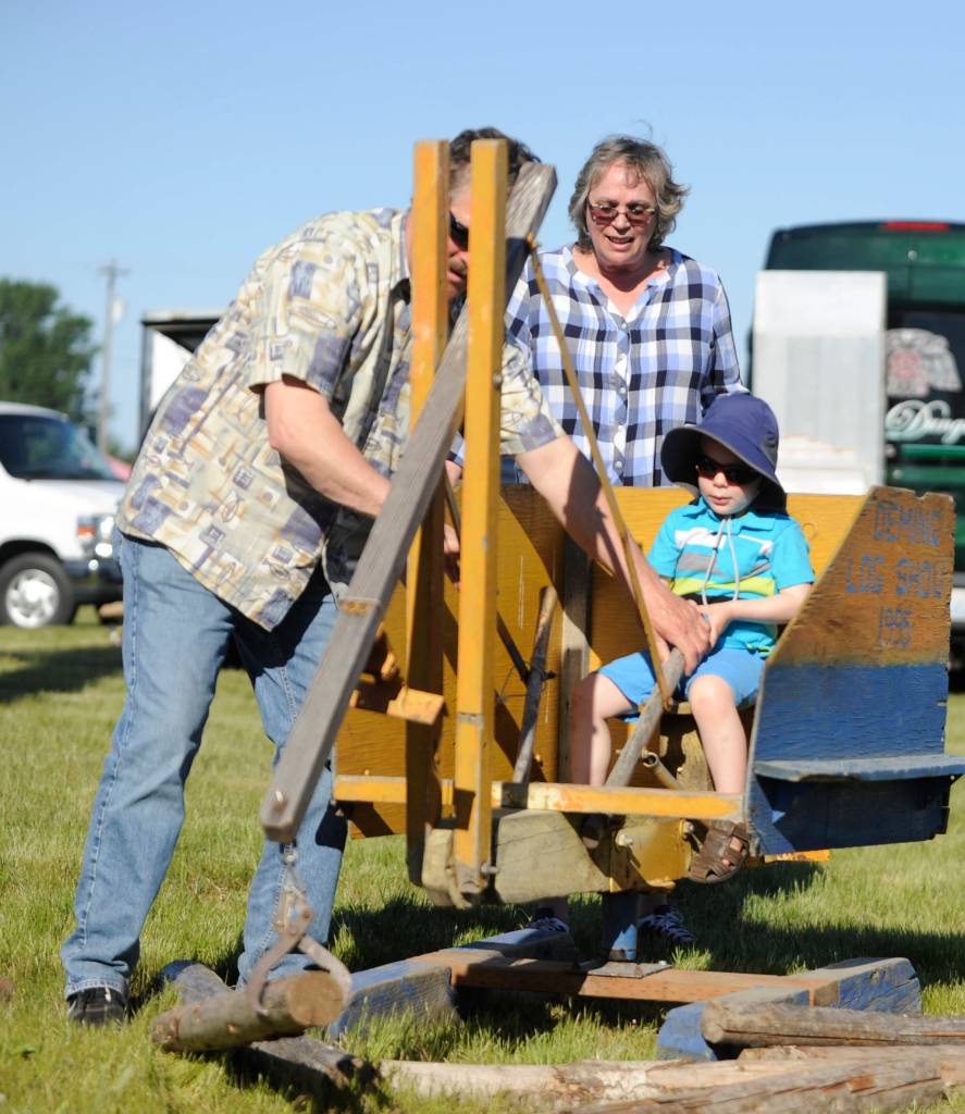 Tim and Kayana Harrison help 2-year-old Austin Williams work on his log-gathering skills at the Sequim Irrigation Festival Logging Show last weekend. Sequim Gazette photo by Michael Dashiell