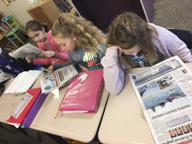 From left, students Anastasia Kovalik, Brooklyn McHaffie-Fatherson and Brooke Piersoll learn about their community from articles in the weekly Sequim Gazette newspaper. Submitted photo