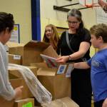 Volunteers, from left, Kelsey Horst, Robyn Bacchus, Christina Crabb, and Louis Crabb pull and begin to sort books on May 22 in Helen Haller Elementarys cafeteria. By the end of the afternoon, thousands of books were bagged for each student to take home as part of the Six Books for Summer program.