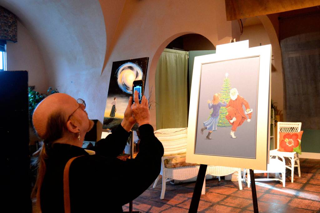 Steven Humphrey, musical director for Another Night Before Christmas snap a shot of art created for the show by Gail McLain. The art piece will be raffled off during its run Dec. 13-22. Sequim Gazette photo by Matthew Nash