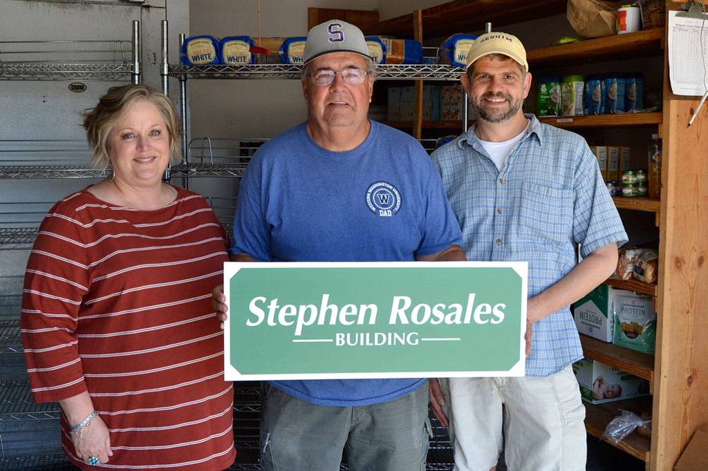 As a surprise, Andra Smith and Mark Ozias, current and former executive director of the Sequim Food Bank, named the bread and meat building after Stephen Rosales, center, for his years of dedication end efforts to help those in-need. Sequim Gazette photo by Matthew Nash