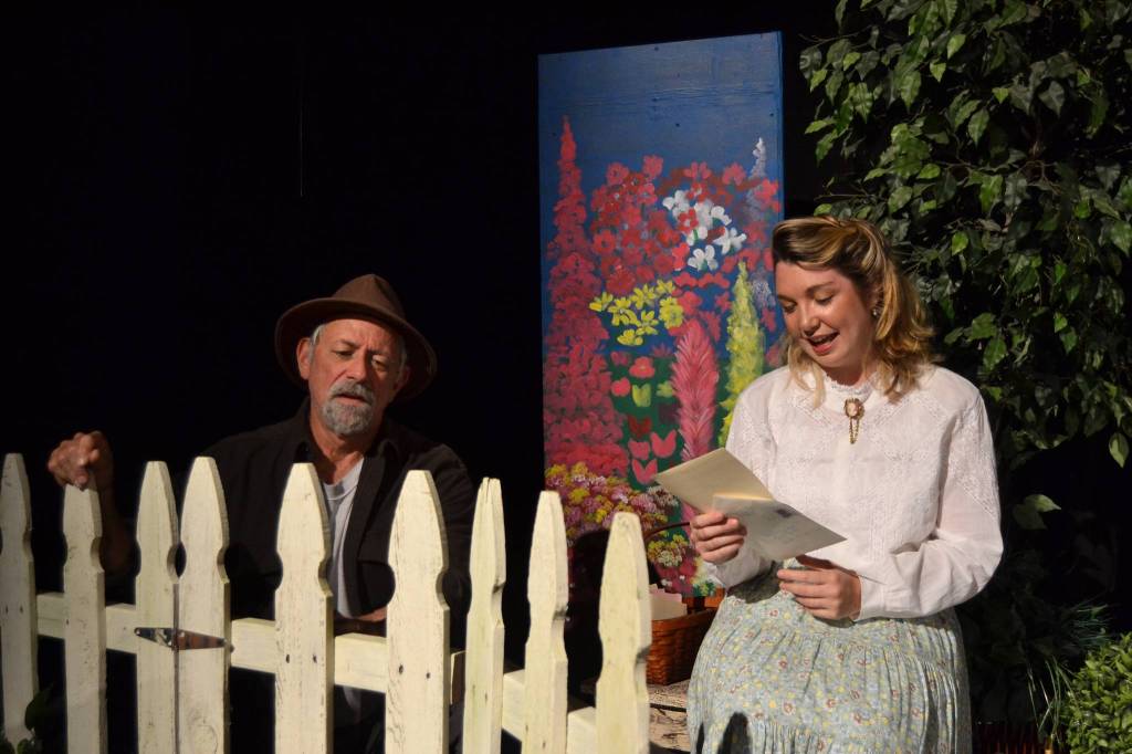 First time actress Kait Saafold reads a letter in her garden as Joe Schulz fixes a fence as an arborist in OTAs Immigrant Garden – Letters. Sequim Gazette photo by Matthew Nash