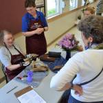 Bev Harn-Fox shows visitors of the Olympic Driftwood Sculptors annual lavender show last year how she prepares a piece of art as Rene Fox shares input. Sequim Gazette file photo by Matthew Nash