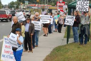 Above, protesters from Indivisible Sequim and other groups, including people from Port Angeles and Port Townsend, hold up signs against the immigrant detention facilities run by Customs and Border Protection, Immigration and Customs Enforcement, and other federal agencies in front of the CBP office in Port Angeles on July 12. By the end of the protest, around 90 people had joined in support. Left, Griffin and Moka Bartch hold a sign asking for federal authorities involved in immigration control to stop bullying children and to stop separating families. Sequim Gazette photos by Conor Dowley