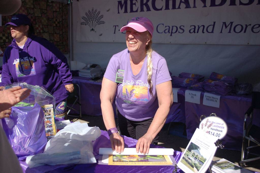 Ellen Riddell sells Sequim Lavender Growers Association merchandise at the Sequim Lavender Festival street fair in 2017. The Street Fair continues at Carrie Blake Community Park for the second summer this weekend. Sequim Gazette file photo by Erin Hawkins