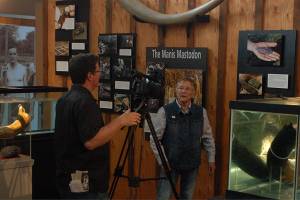 Clare Manis Hatler, center, discusses the Manis Mastodon in the new Sequim Museum & Arts building. She was being interviewed by KBTC associate producer Chris Anderson, left, for a segment of the Northwest Now web program. Sequim Gazette photo by Conor Dowley