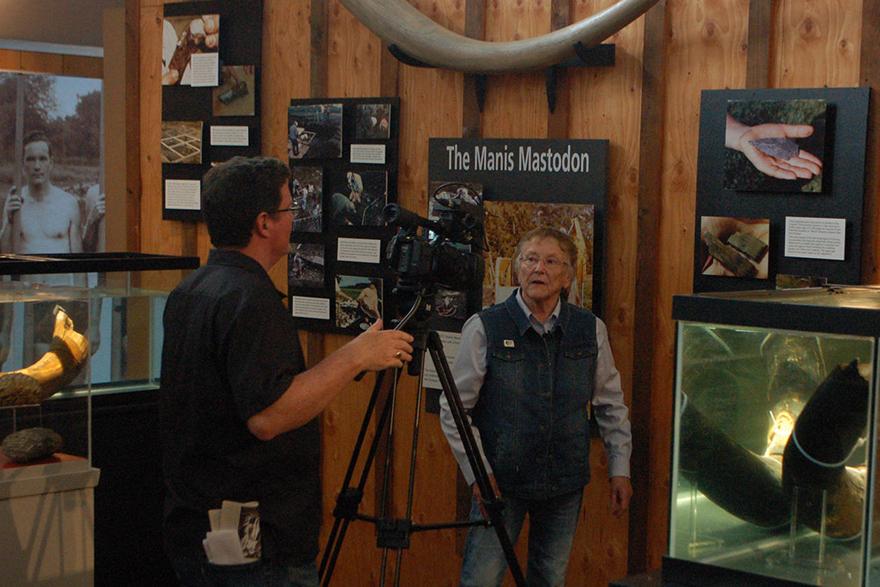 Clare Manis Hatler, center, discusses the Manis Mastodon in the new Sequim Museum & Arts building. She was being interviewed by KBTC associate producer Chris Anderson, left, for a segment of the Northwest Now web program. Sequim Gazette photo by Conor Dowley