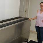 Brianne Moores of Moores Blind Cleaning stands with her companys ultrasonic blind cleaning machine. The eight-foot long machine can work with multiple sets of blinds at a time, and cleans them thoroughly using a combination of a mild cleaning solution and ultrasonic waves. Sequim Gazette photo by Conor Dowley