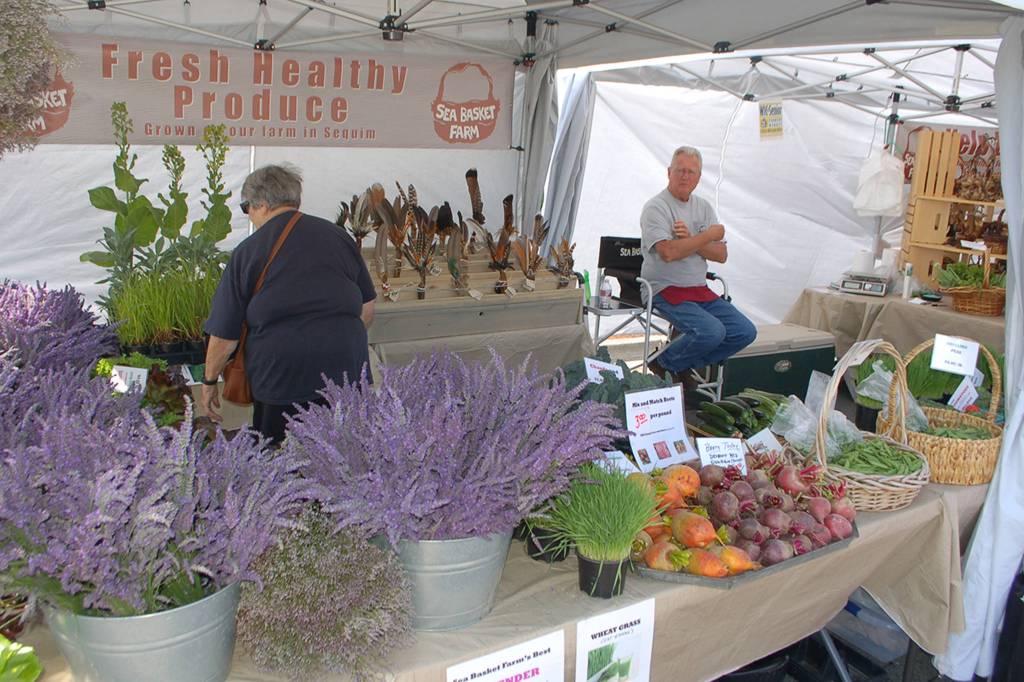 Greg Gundy of Sea Basket Farm sits in his booth at the Sequim Farmers Market during the Lavender Festival. Greg and his wife Marilyn brought a special larger version of their booth, where they sell various vegetables, herbs and hand-made kelp baskets and ceremonial items. Sequim Gazette photo by Conor Dowley.