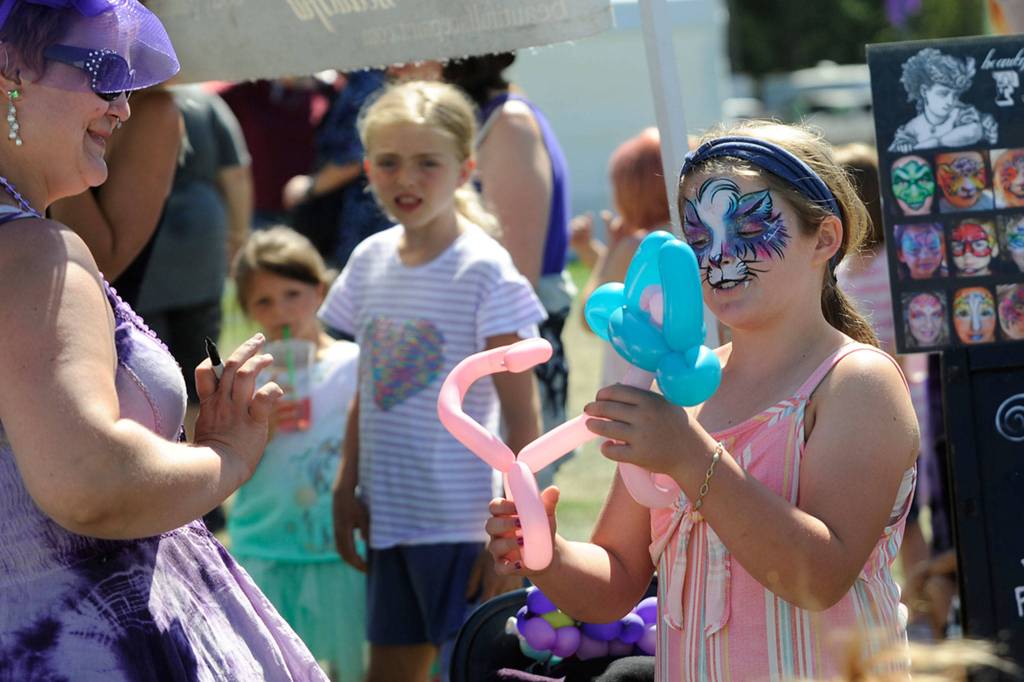 At the Sequim Lavender Festival Street Fair, Shannon Olsen, 8, of Port Orchard, takes a balloon monkey she got from Lily the Fairy at the Chelle Beautiful of Bellingham booth. Shannon said she also got a galaxy fox painted on her face, too. Sequim Gazette photo by Matthew Nash