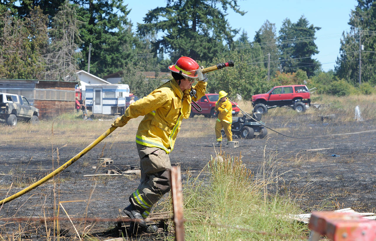 Fire District 3 personnel put out hot spots at a brush fire in Carlsborg on July 26. Sequim Gazette photo by Michael Dashiell