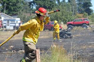 Fire District 3 personnel put out hot spots at a brush fire in Carlsborg on July 26. Sequim Gazette photo by Michael Dashiell