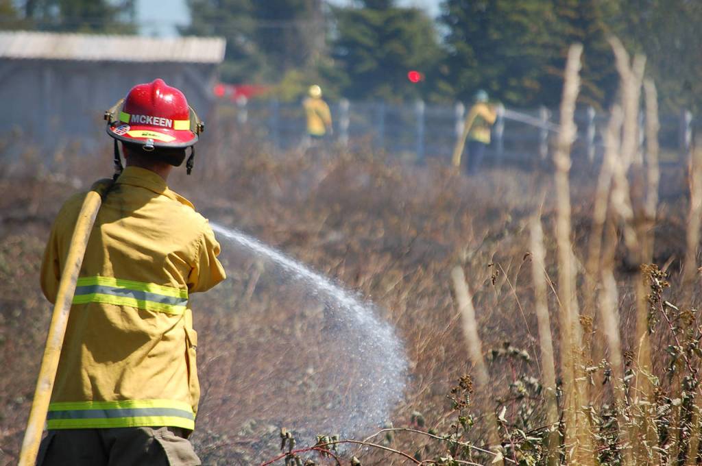 Fire District 3 personnel working on hot spots at a brush fire that burned almost two acres in Carlsborg on July 26. Sequim Gazette photo by Conor Dowley.