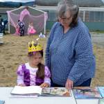 Left, Cherrie Bishop reads to her granddaughter Reagan Hiner, 4, a copy of Princess Hyacinth and the surprise tale of a girl who floated. Reagan was one of many children to dress up for Princess Storytime. She was proud to be dressed as Belle and wearing Tinkerbell shoes, she said. Right, Azlyn Blessington, 4, gets help from her mom Carolyn Raleigh to put on her new crown dressed as a fairy princess at the Princess Storytime.