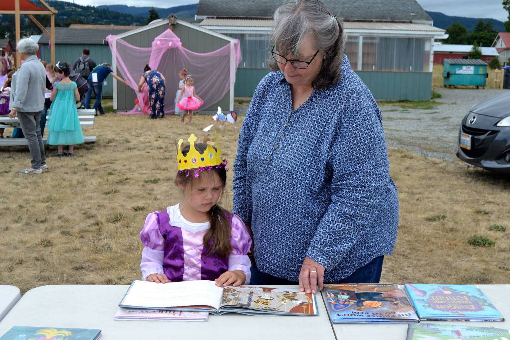 Left, Cherrie Bishop reads to her granddaughter Reagan Hiner, 4, a copy of Princess Hyacinth and the surprise tale of a girl who floated. Reagan was one of many children to dress up for Princess Storytime. She was proud to be dressed as Belle and wearing Tinkerbell shoes, she said. Right, Azlyn Blessington, 4, gets help from her mom Carolyn Raleigh to put on her new crown dressed as a fairy princess at the Princess Storytime.